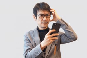 スマホを見て頭を抱えている男性